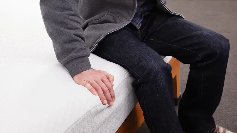 A person sitting on the edge of the Tuft & Needle Original mattress
