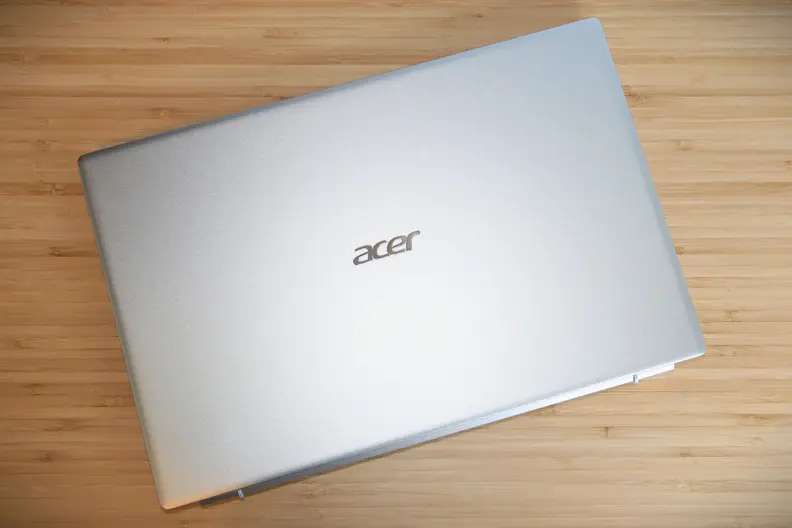 A closed silver laptop showing a company logo on top of a light brown wooden surface.