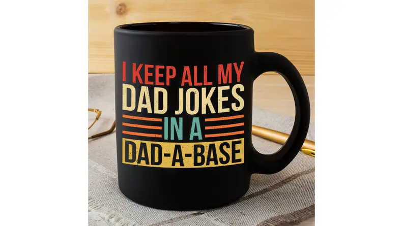 Black mug that says "I Keep All My Dad Jokes In A Dad-A-Base"
