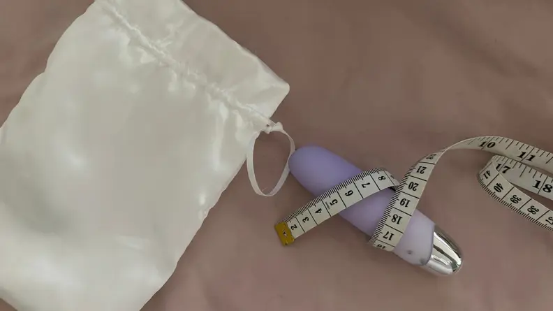 Vibrator on a pink sheet with measuring tape