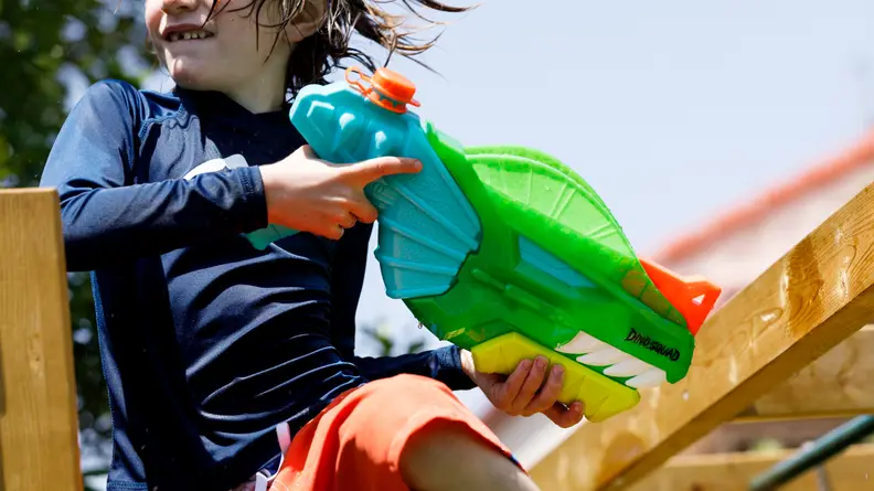 A boy uses the Nerf Dino-Soak Super Soaker