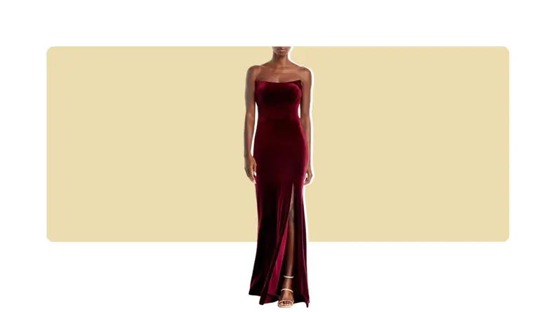 A model wearing a dark red velvet strapless gown with a leg slit.