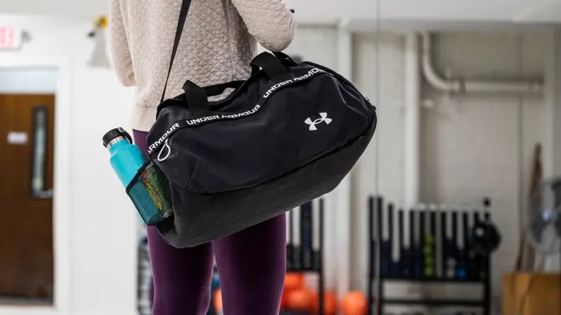 A woman carrying a duffel bag on her shoulder.