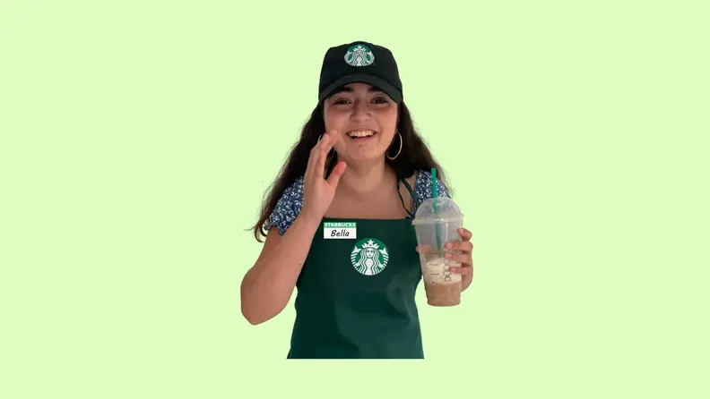 A child modeling a Starbucks barista uniform in front of a green background.