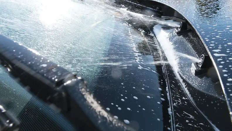A close-up of fluid getting sprayed onto a windshield.