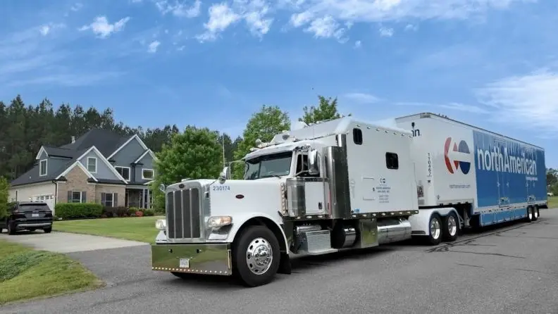 A hauling truck parked on a street in front of a house