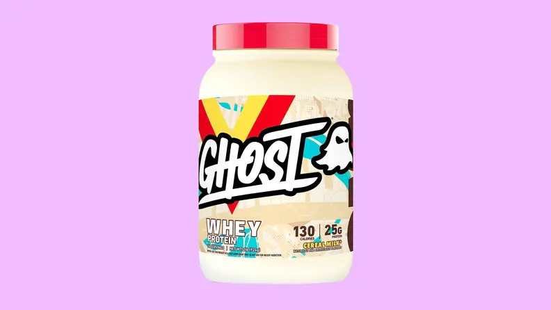 A beige container of Ghost Whey Protein powder on a light purple background.