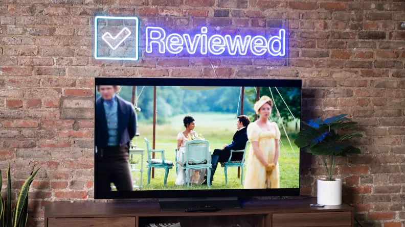 LG C2 in front of brick wall next to potted plants with movie playing on screen.