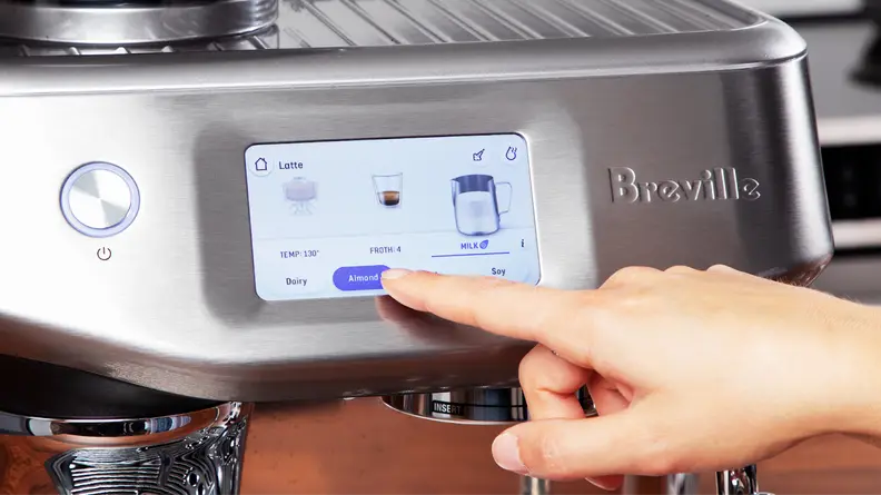 Person using finger to make dairy selection on the Breville Barista Touch Impress' touchscreen display.