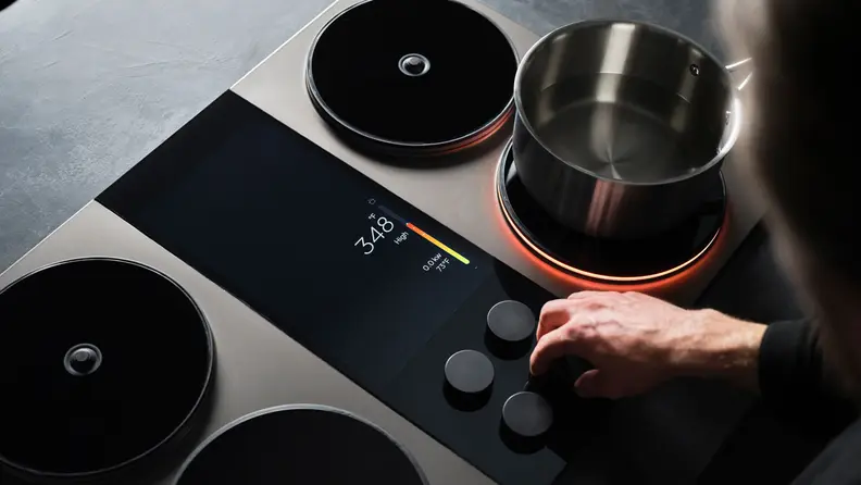 Close-up of a hand adjusting a knob on the Impulse Induction cooktop.