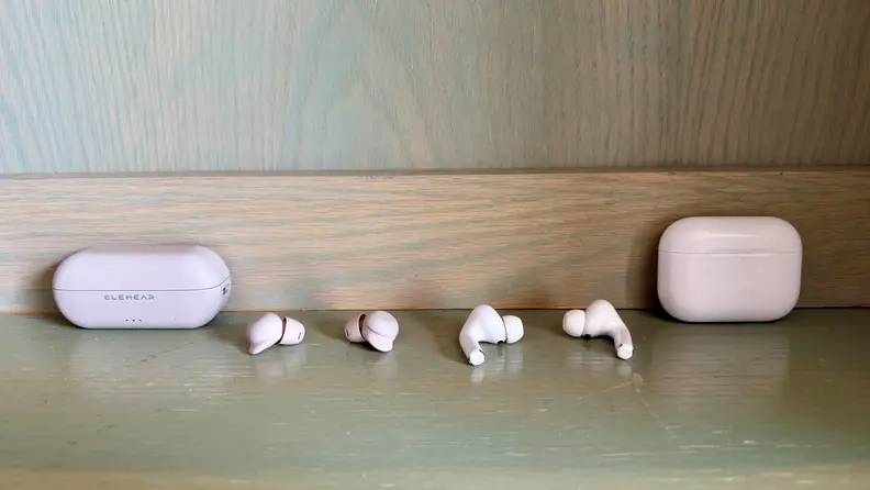 ELEHEAR Delight Hearing Aids shown next to AirPods Pro on a light wooden surface.