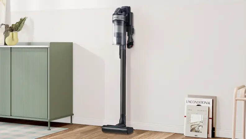 A stick vacuum stands up against a white wall