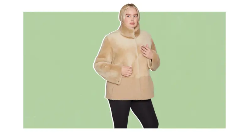 A model wearing a khaki-colored shearling jacket that has two textures on the top and bottom halves.