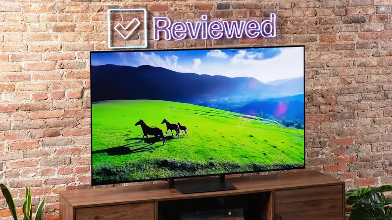 The Samsung S90C QD-OLED TV on an entertainment center on a brick background.