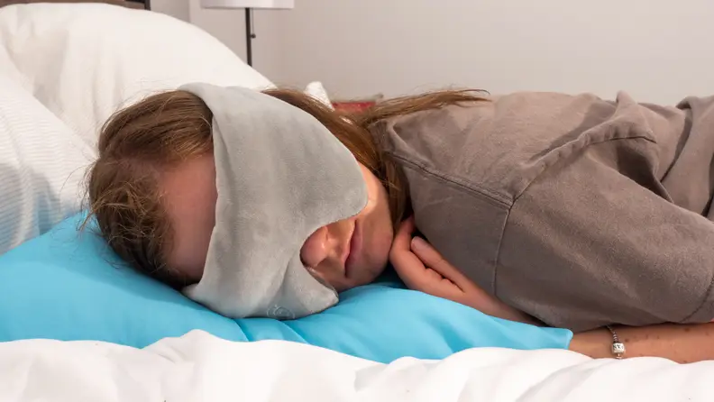 Person laying on bed with weighted eye mask on.