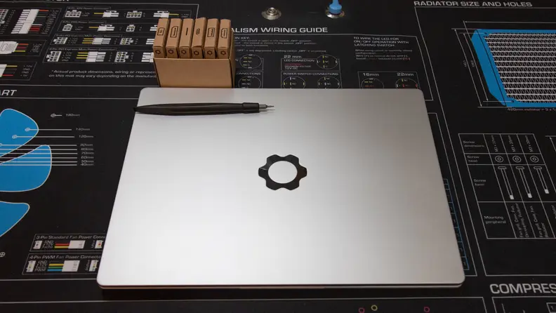 A screwdriver and cardboard box lie on the Framework laptop's lid.