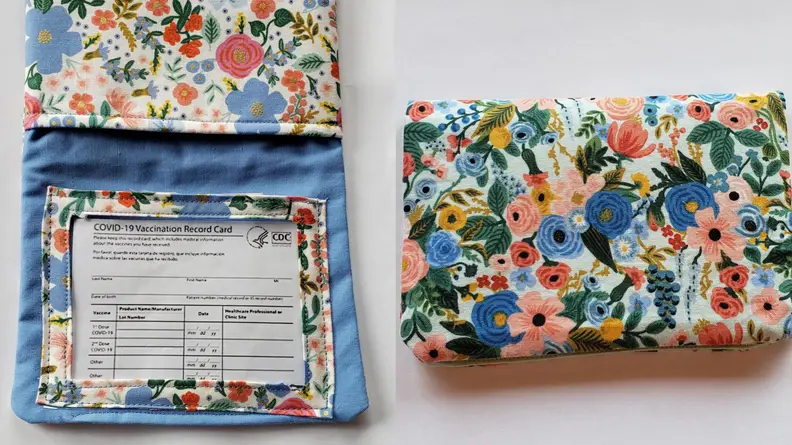 A COVID vaccine card in a vinyl holder in a case with floral Rifle Paper Co. fabric.