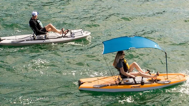 Two Lynx pedal kayaks on the water. One has a blue sunshade attached,