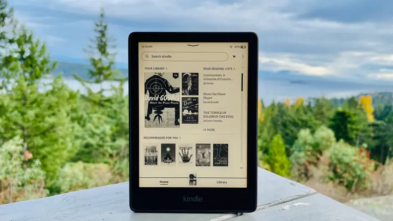 A Kindle Paperwhite, the best kindle you can buy, sits on an outdoor table, against an overcast sky.