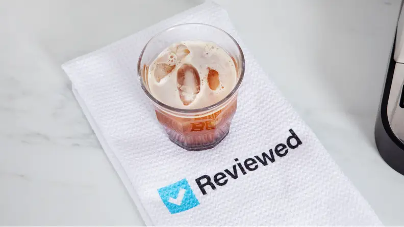 A cup of coffee on top of a napkin with the Reviewed logo.