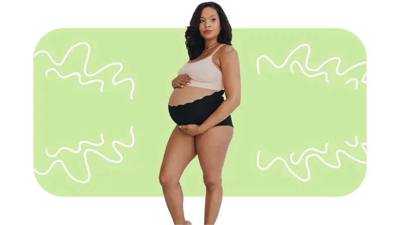 Pregnant model wearing light pink support bra top and solid black high rise underwear while holding baby bump.