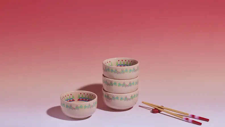 Four rice bowls, chopstick sets, and chopstick resters on red background