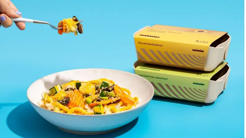 A person holding a fork filled with pasta and the bowl filled with pasta sitting beneath.