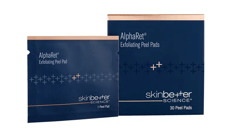 A navy blue box and a packet of exfoliating pads side by side on a white background.