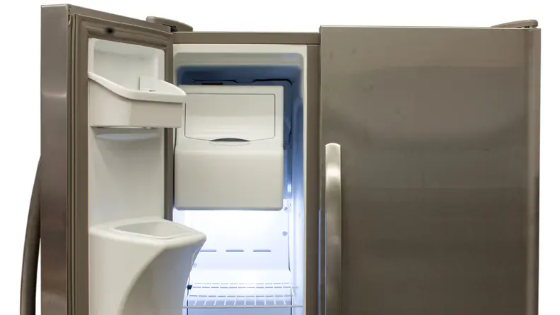 The top half of the Frigidaire FFSS2615TS side-by-side refrigerator, with the freezer door open to reveal its ice maker, racks, and storage bins built into the door's moulding.
