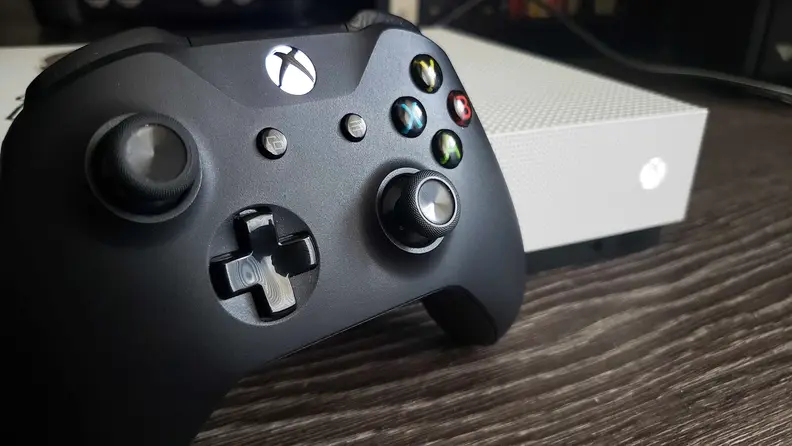 A close-up of an Xbox controller next to an Xbox console