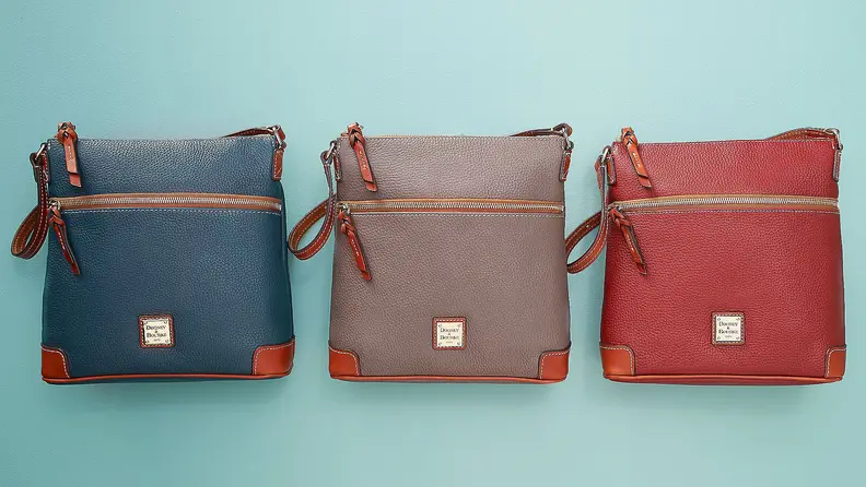 Three Dooney & Bourke leather bags in blue, grey, and red on teal background