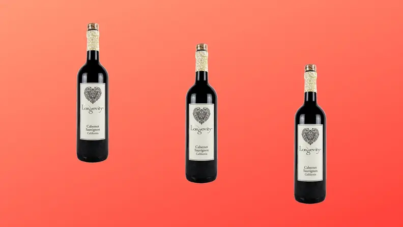 Three bottles of Longevity Cabernet Sauvignon wine are arranged across a red gradient background.