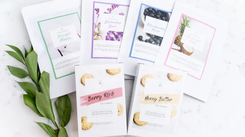 A brightly lit top-down photo of tea blends and tea cookies, featuring shades of white and pastels.