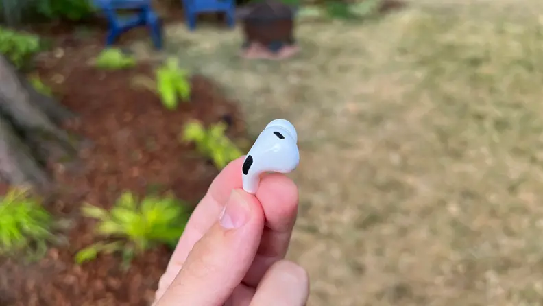 A close-up of a hand holding a single earbud of the Apple AirPods Pro (second gen).