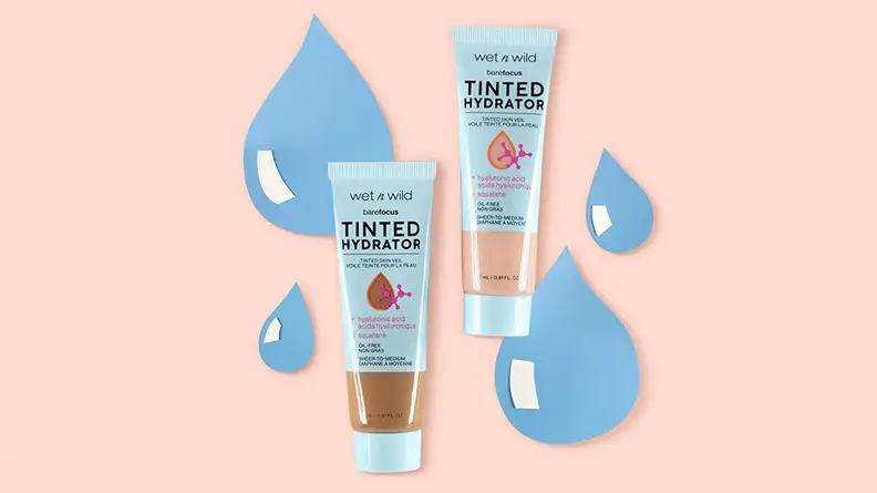 Two Wet n Wild Bare Focus Tinted Hydrators in light and dark skin tones sitting on top of a light pink background with animated water droplets in back of them.