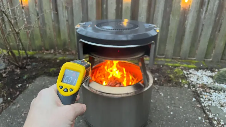 Person holding up thermometer to open flame inside the Solo Stove Pi Fire pizza oven.