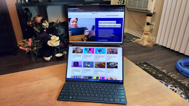 A dual screen laptop propped up with one display stacked on top of the other. A small keyboard sits in front at the bottom.