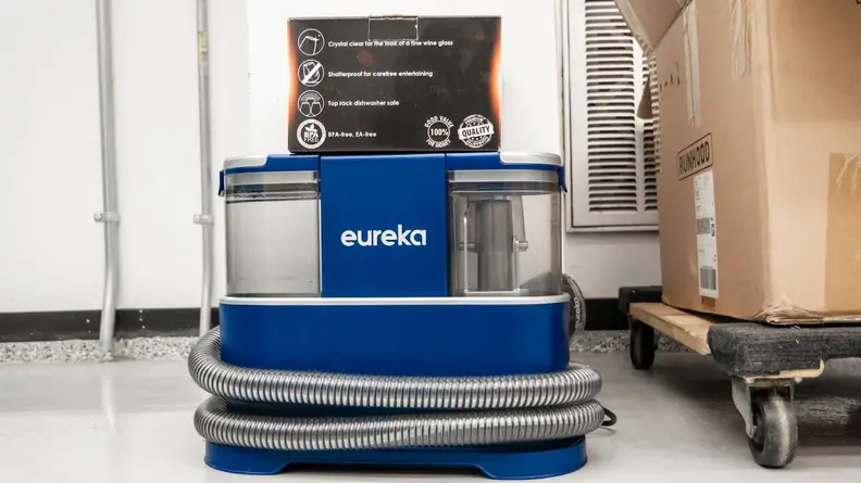 A small box on top the Eureka NEY100 carpet cleaner next to large cardboard box.