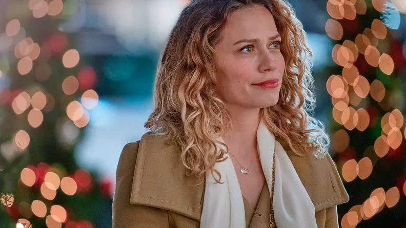 Emily (Bethany Joy Lenz) is gorgeously lit by the red and gold glow of Christmas tree lights in a shot from 2021's made-for-TV movie An Unexpected Christmas.