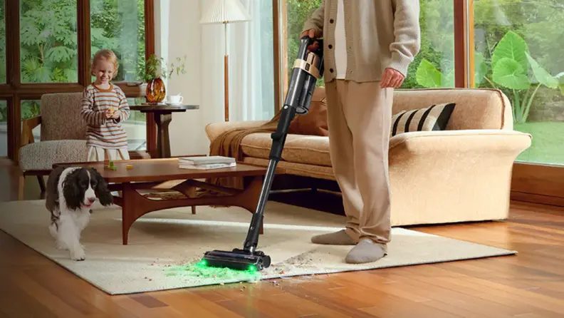 A person vacuums a carpet in front of a baby