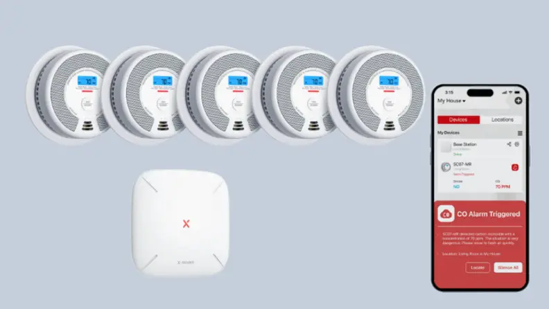 5 smoke detectors, a base, and a phone sit on a gray background