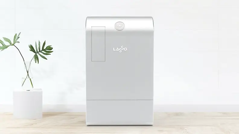 A large silver machine is on display in a minimalist office environment. This is a Lasso recycling machine.
