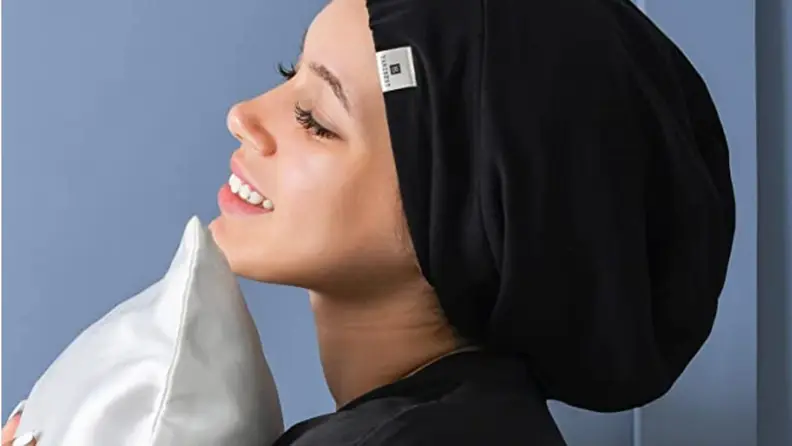 a woman wearing the yanibest bonnet holds a pillow