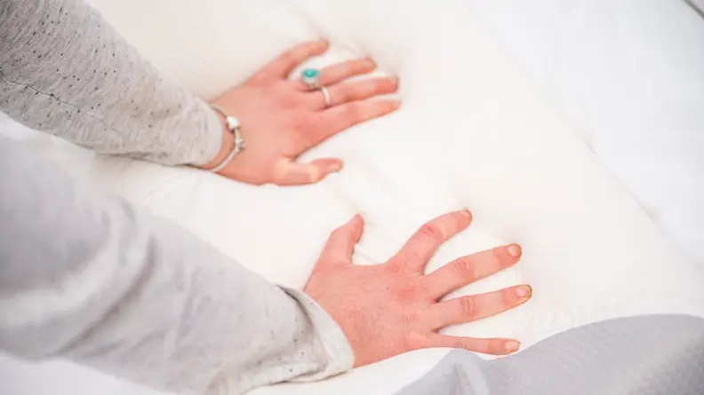 Hands pushing down on the pillow.