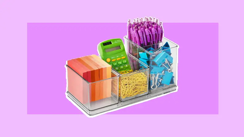 Clear acrylic desk organizer filled with multi-colored post-it notes, green calculator, purple clickable pens, yellow paperclips, and blue paper clamps.