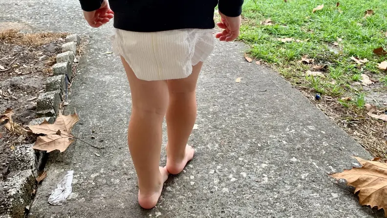 A child with their back to camera wearing a pair of white diapers
