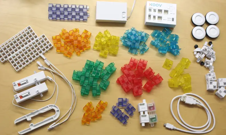 The KOOV Trial Kit includes blocks, sensors, LED lights, motors, a battery pack, and the KOOV core, which is the input/output board.