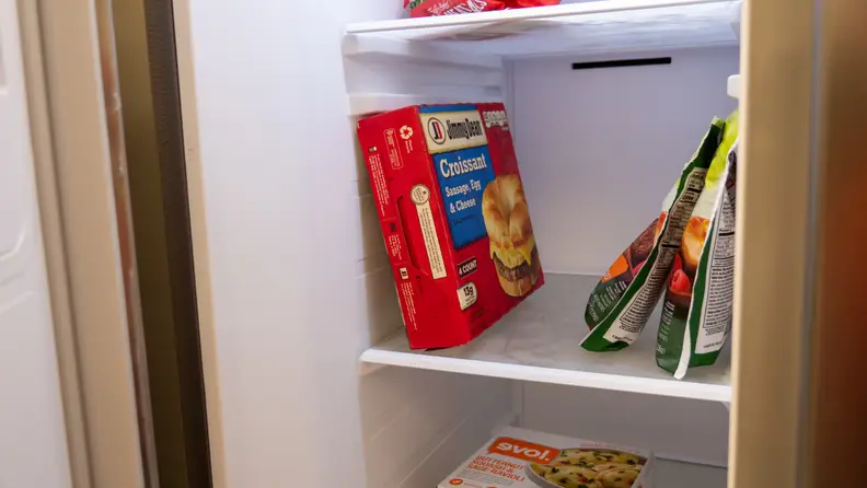 A close-up of the Samsung RS27T5561SR side-by-side refrigerator's freezer shelves, with some common items stored there for scale. A box of breakfast sandwiches standing tall takes up about 80% of the shelf's height.