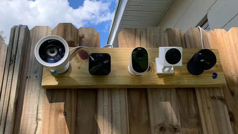Five security cameras mounted on a wooden fence