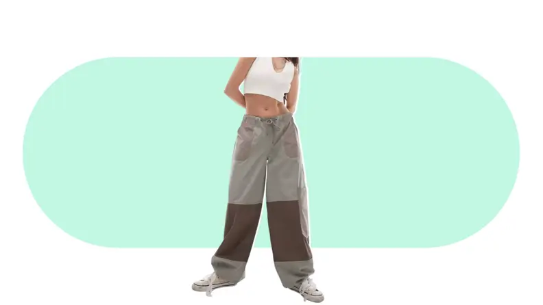 A model seen from the waist down, wearing parachute pants that are green and brown colorblocked.
